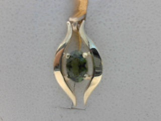 Oval green tourmaline pendant set in curved 9ct yellow gold frame